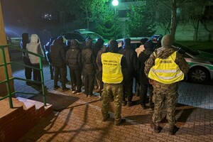 Zatrzymani przy granicy z Litwą Zatrzymani migranci stojący przed funkcjonariuszem i żołnierzem WOT