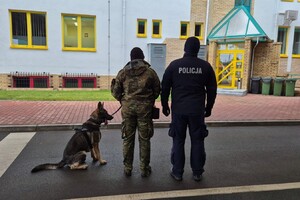 Szkolenie psów służbowych Funkcjonariusz Policji i Straży Granicznej plecami, funkcjonariusz Straży Granicznej trzyma psa na smyczy