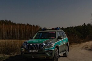 Nocny patrol Ato straży granicznej stoi w nocy na polnej drodze, na tle gwieździstego nieba