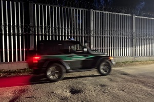 Pojazd Straży Granicznej Pojazd Straży Granicznej jadący nocą wzdłuż bariery fizycznej.