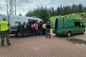 Cudzoziemcy zatrzymani przy polsko - litewskiej granicy Grupa zatrzymanych cudzoziemców stojących przy służbowym aucie