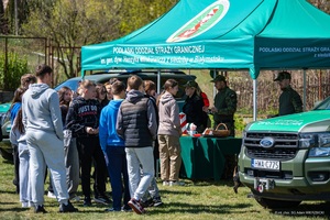 Spotkanie z funkcjonariuszami Straży Granicznej – Dzień otwarty Grupa młodzieży stoi przed stoiskiem prezentującym sprzęt używany w Straży Granicznej.