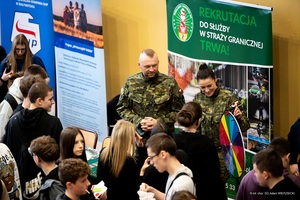 Spotkanie z funkcjonariuszami Straży Granicznej – Dzień otwarty Młodzież stoi przy stoisku promocyjnym Straży Granicznej.