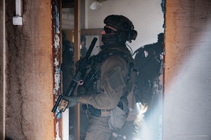 Wspólne ćwiczenia Straży Granicznej i Krajowej Administracji Skarbowej Funkcjonariusz z bronią w budynku.