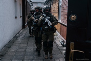 Wspólne ćwiczenia Straży Granicznej i Krajowej Administracji Skarbowej Funkcjonariusze z bronią wchodzą do budynku.