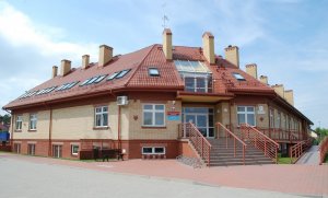 Widok na cały budynek. Duży budynek z czerwonym dachem i schodami prowadzącymi do wejścia.